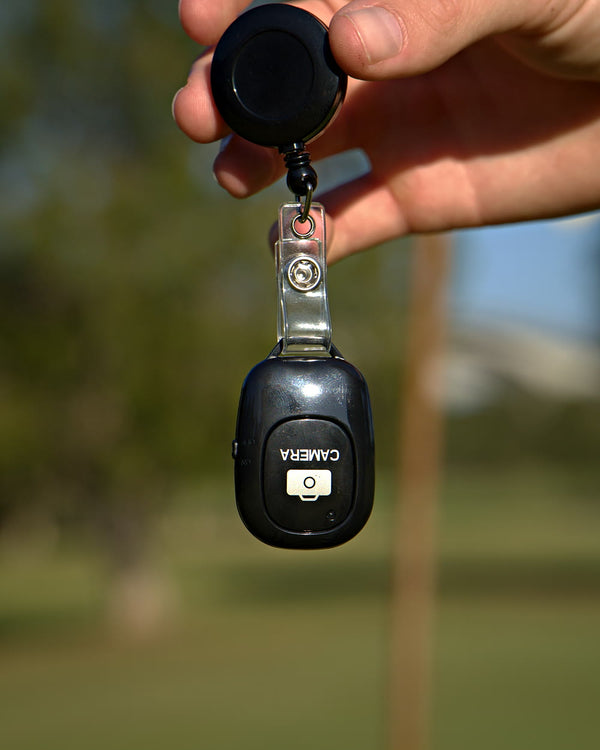The Clippar Bluetooth clicker on its retractable badge reel, held on the course