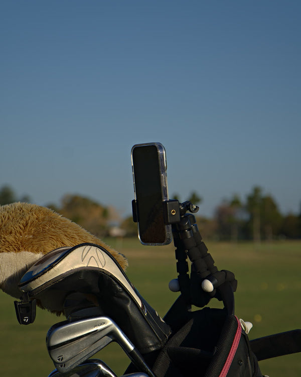 The Clippar phone holder's bendable legs wrapped round a golf bag, iPhone clamped on top